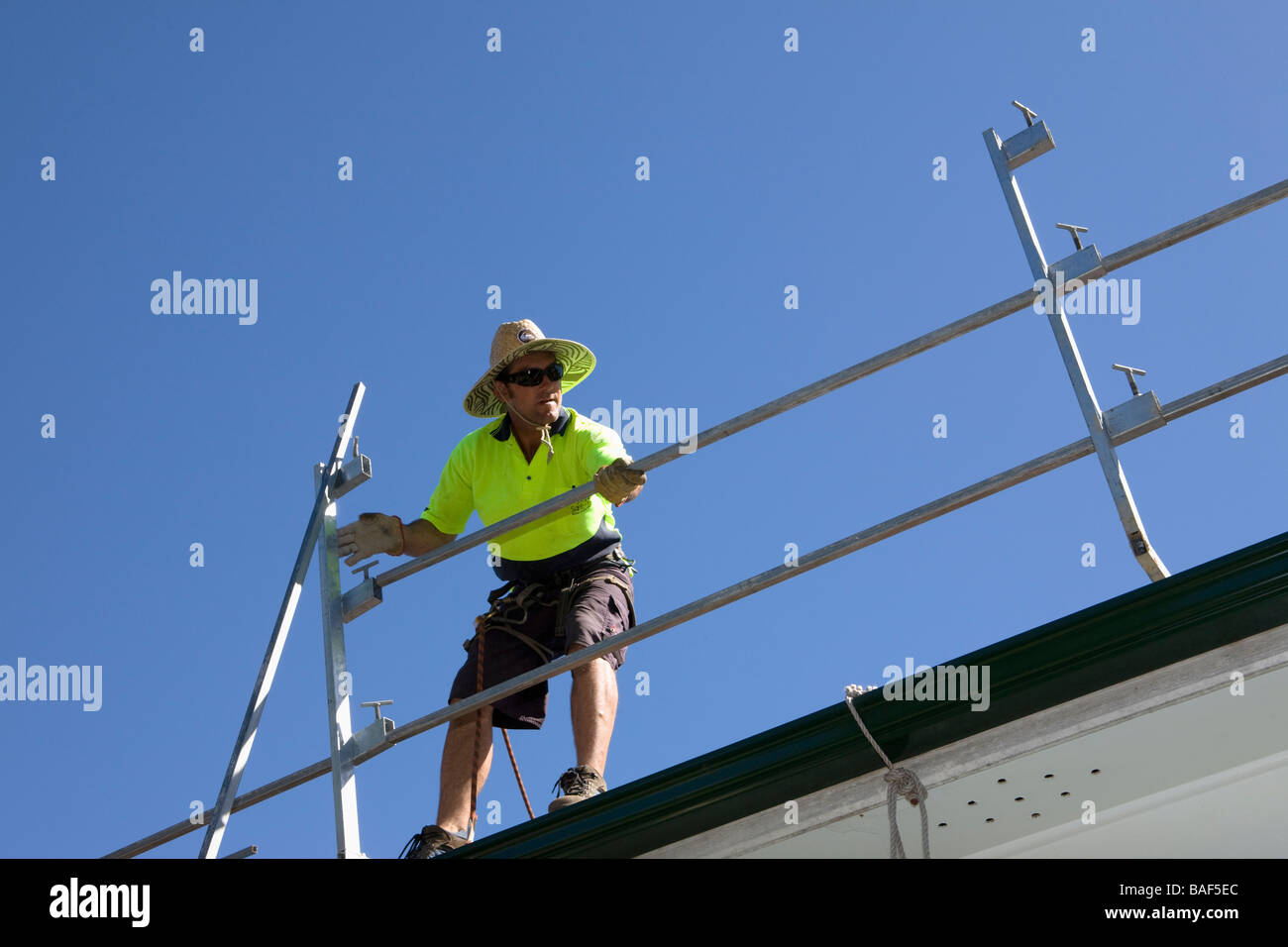 Uomo di erigere di rotaie di sicurezza attorno a terra cotta tetto di tegole, Sydney, Nuovo Galles del Sud, Australia Foto Stock