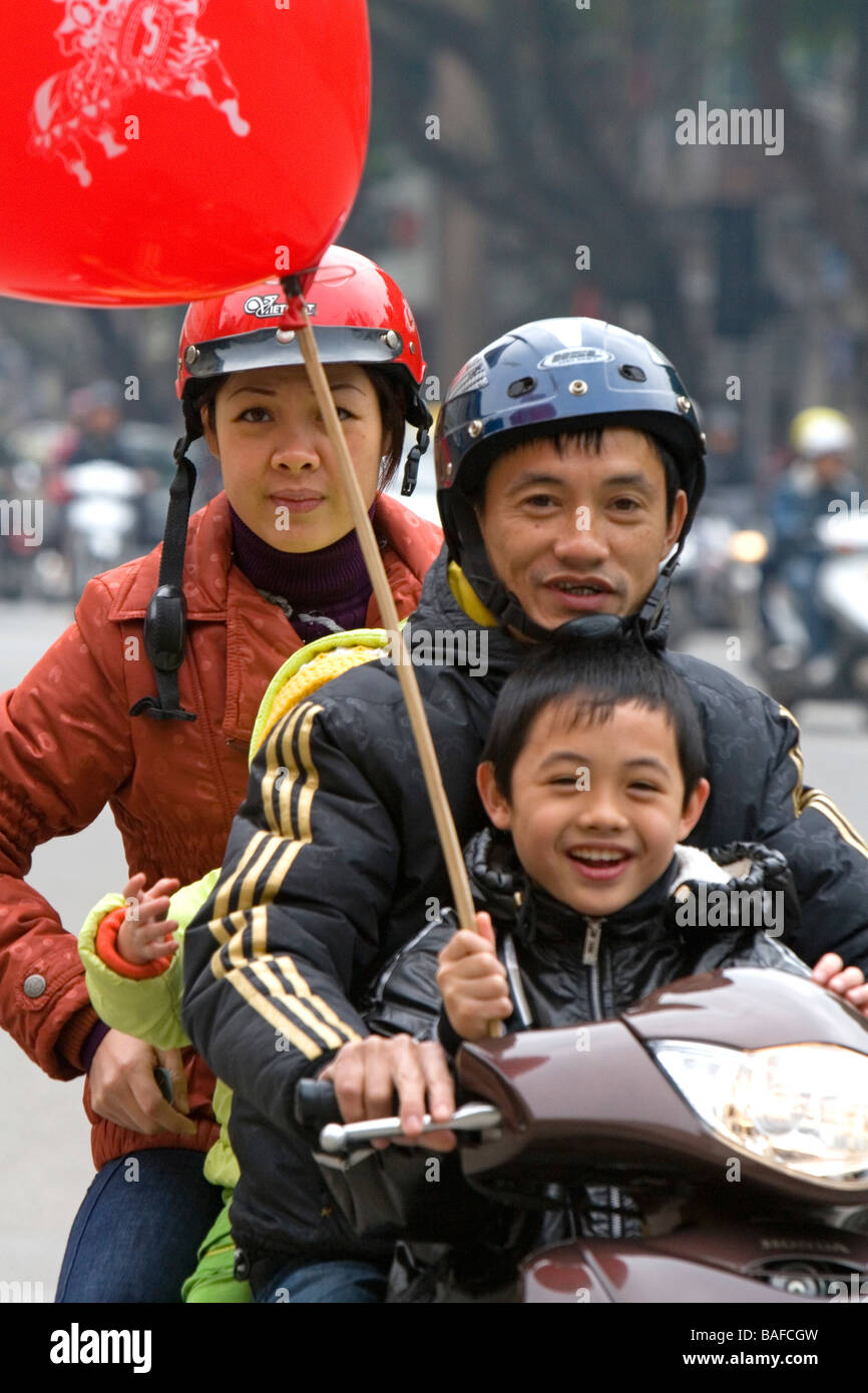 Famiglia vietnamita su una moto acquistare un pallone da un venditore ambulante di Hanoi, Vietnam Foto Stock