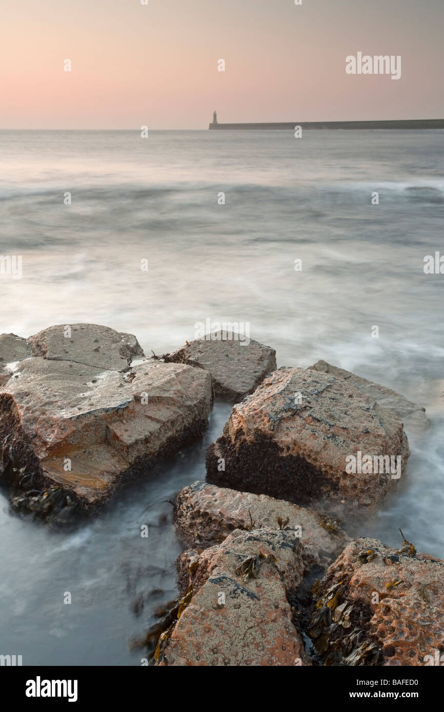 Onde che si infrangono contro gli scogli di nitidezza punto illuminato di Tynemouth dalla mattina presto luce a molla Foto Stock