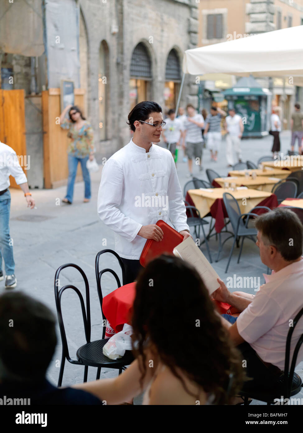 Un cameriere serve la gente a un cafe' all'aperto in Italia. Foto Stock