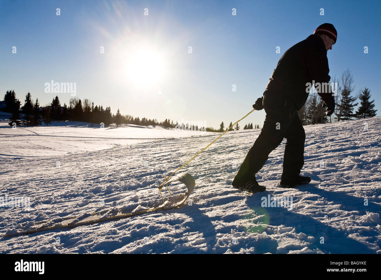 Silhouette di un uomo; l'uomo tira un toboggan Foto Stock