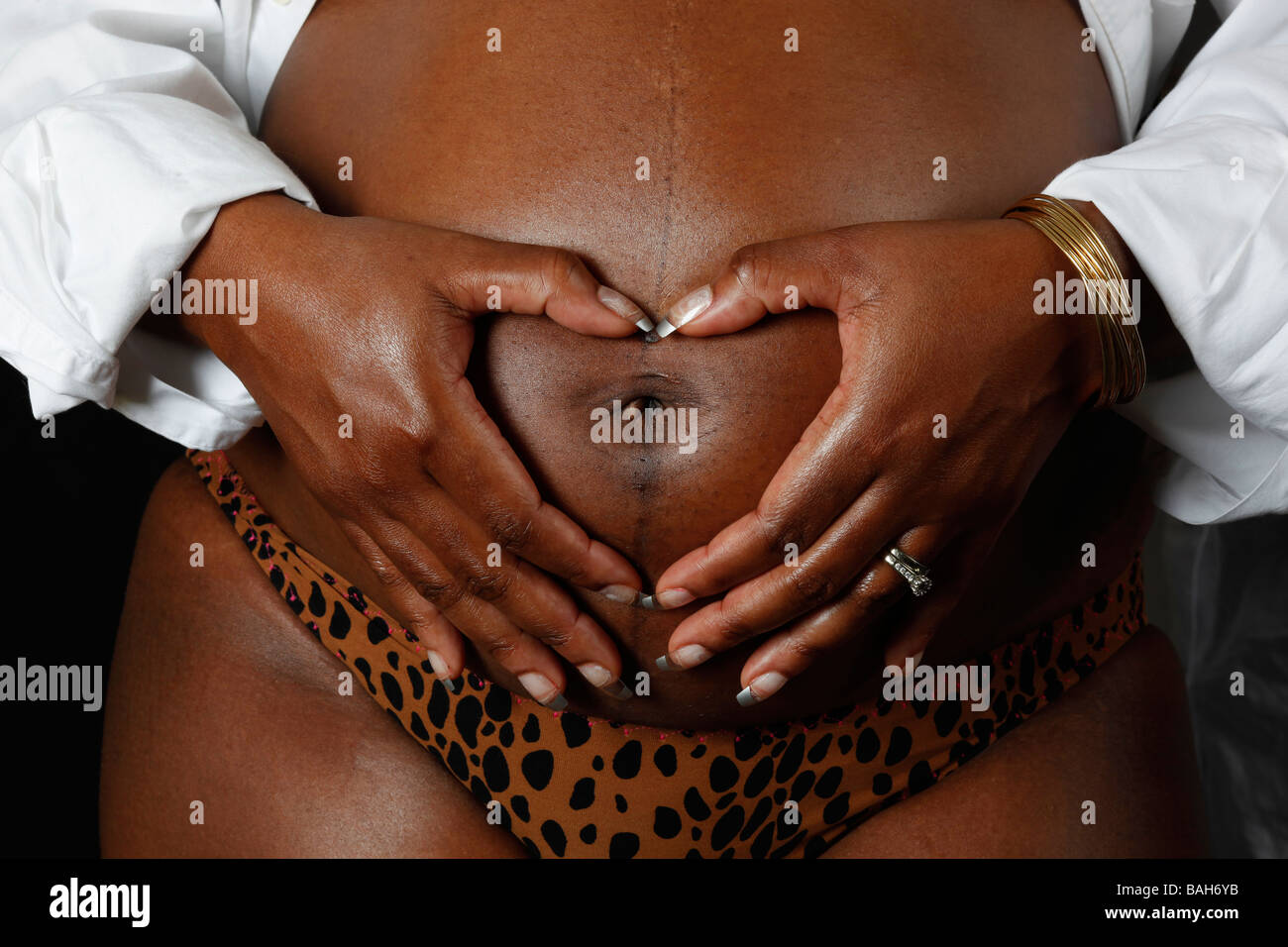 Donna incinta con mani messa a forma di cuore Foto Stock