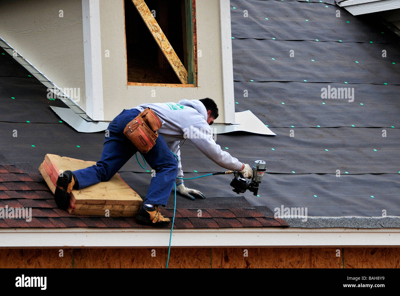Un uomo ispanico chiodi tegole sul tetto di una nuova casa in Oklahoma City, Oklahoma, Stati Uniti d'America. Foto Stock