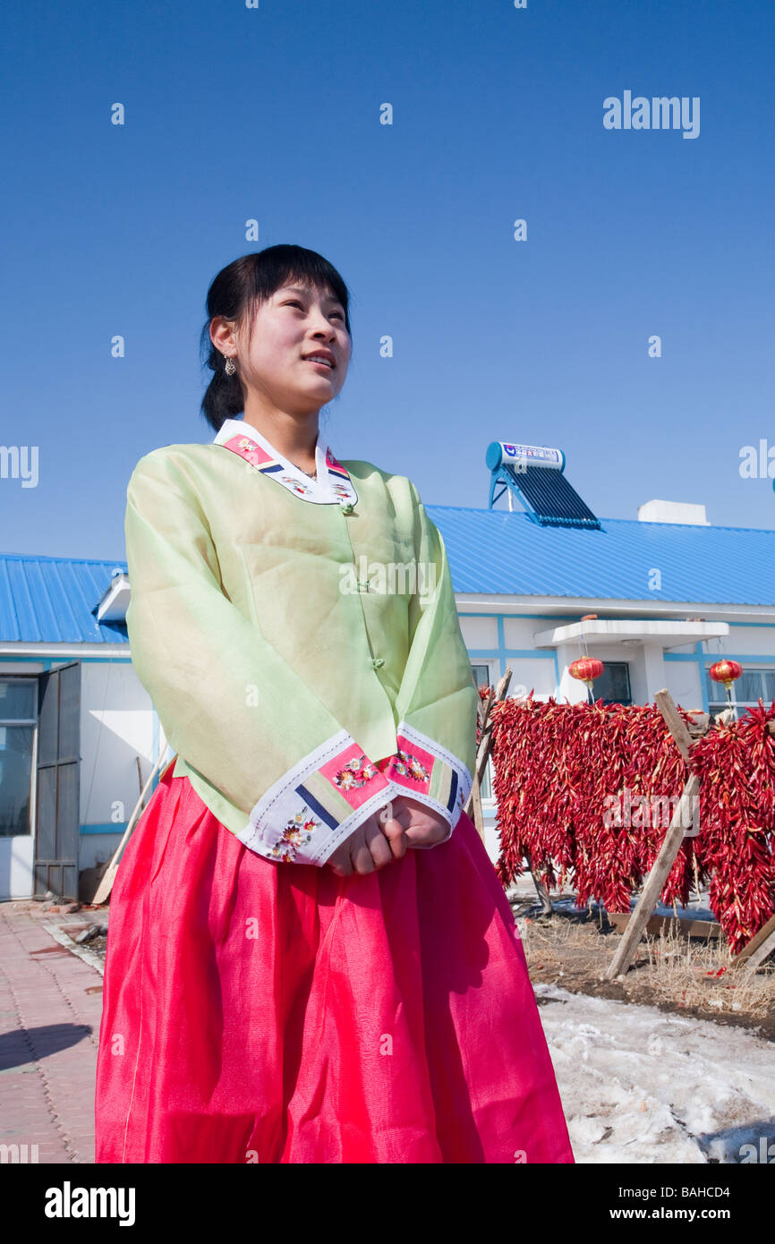 Un agricoltore in Cina fuori la sua casa colonica con calorifero di acqua solare sul tetto Foto Stock