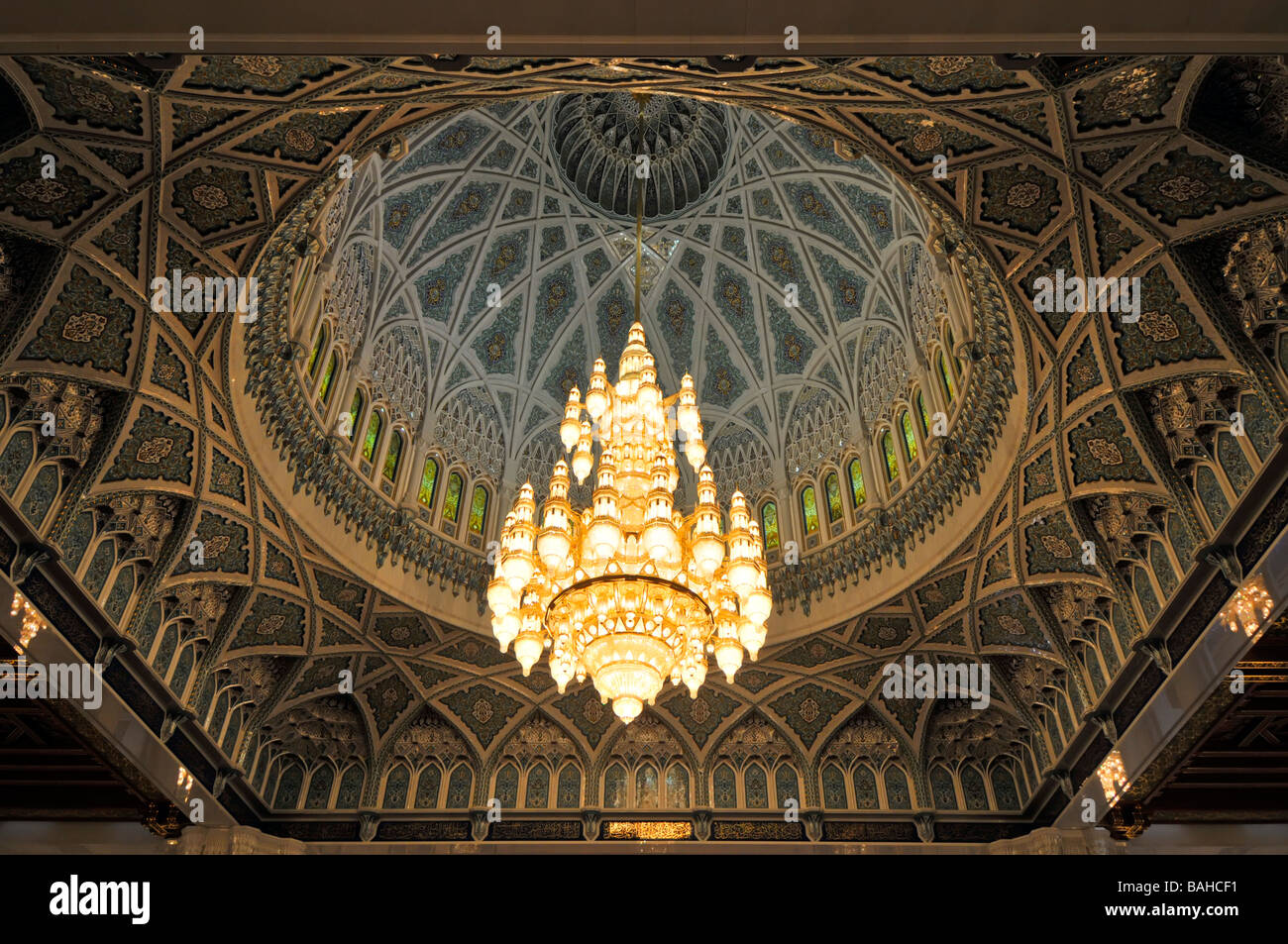 Il Muscat Oman grande moschea interni la sala da preghiera con grande lampadario appeso al di sotto la cupola ornata Foto Stock