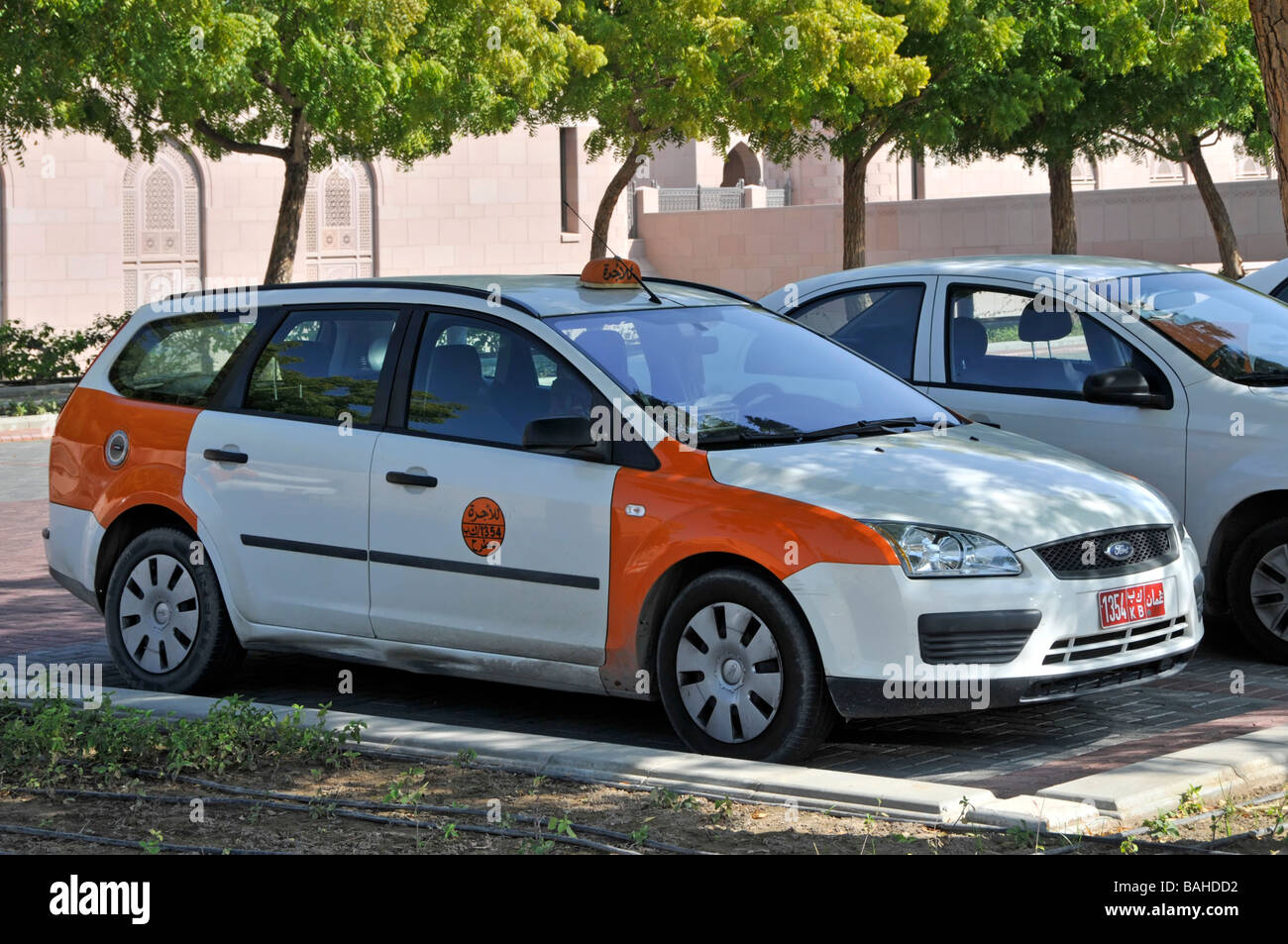 Vista laterale e frontale cabina taxi con codice colore ufficiale arancione e bianco selezionati pannelli carrozzeria scelti in colore Muscat Oman sul Golfo di Oman Medio Oriente Foto Stock