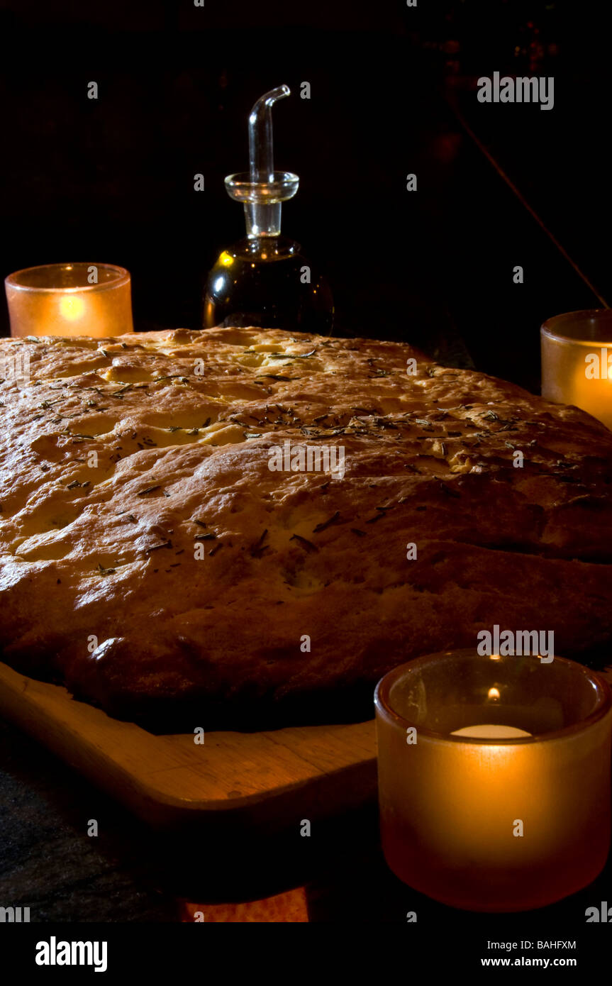 Grandi artigianale di pane focaccia circondata da candele e e olio di oliva su un tagliere. Foto Stock