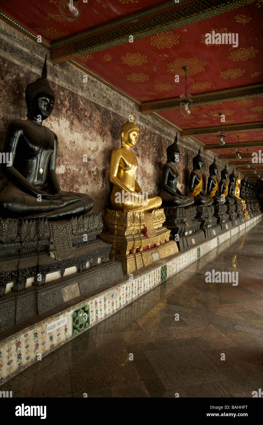 Una fila di nero e oro statue di Buddha linea le gallerie al Wat Suthat tempio a Bangkok Foto Stock