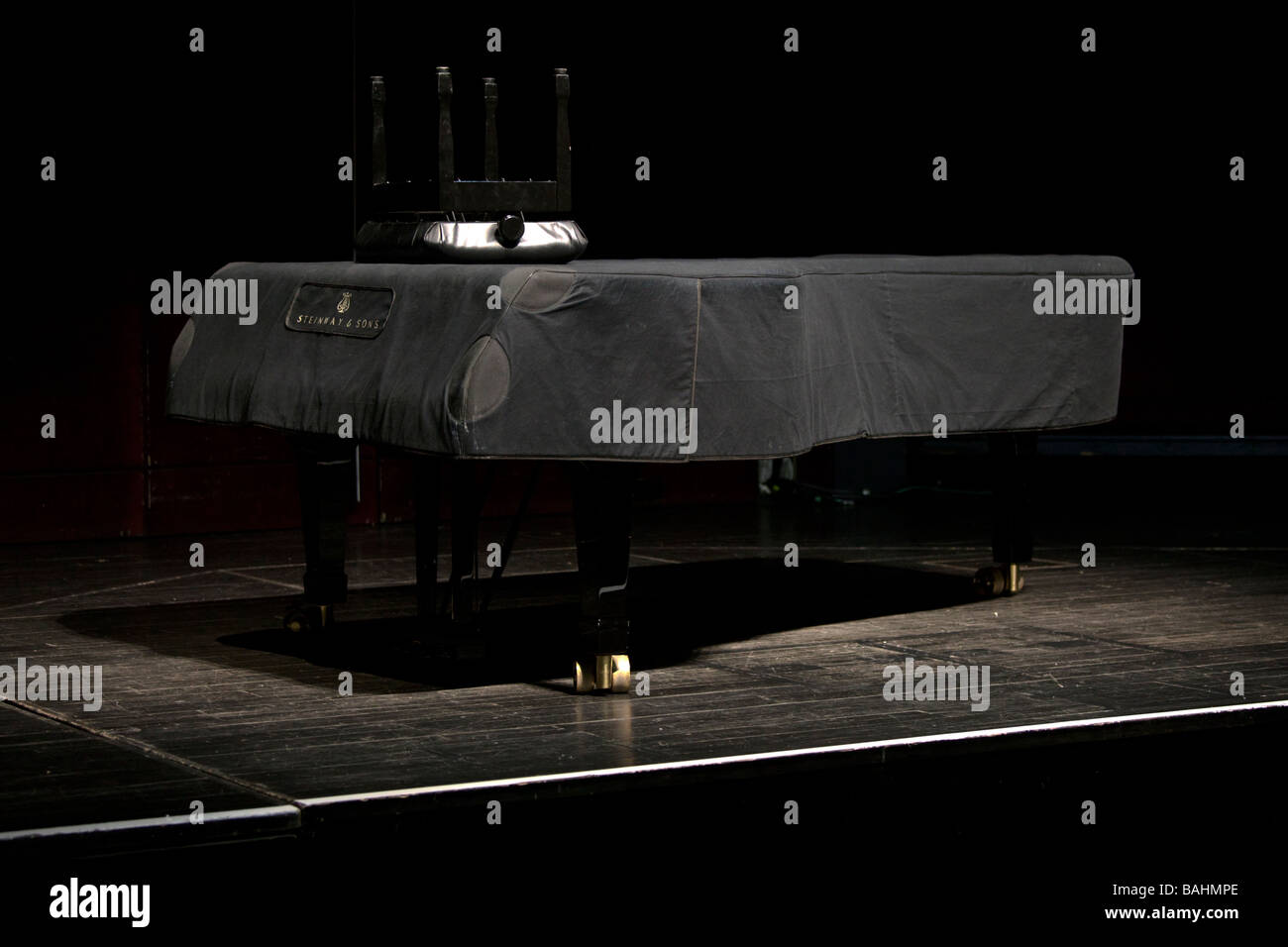Un piano Steinway coperto sul palco con sgabello rovesciato Foto Stock
