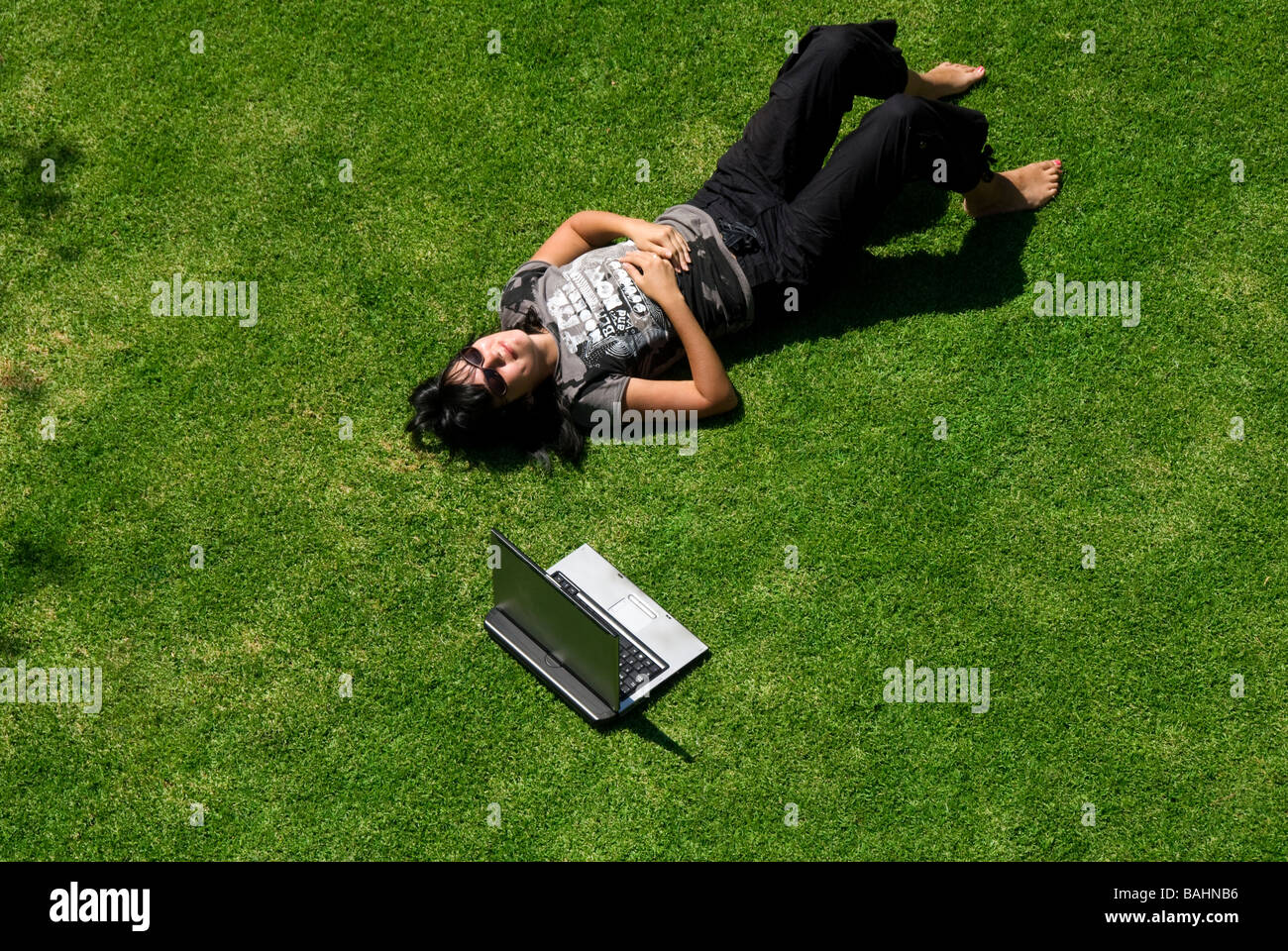 Una donna con un computer portatile in giardino, sdraiati sull'erba Foto Stock