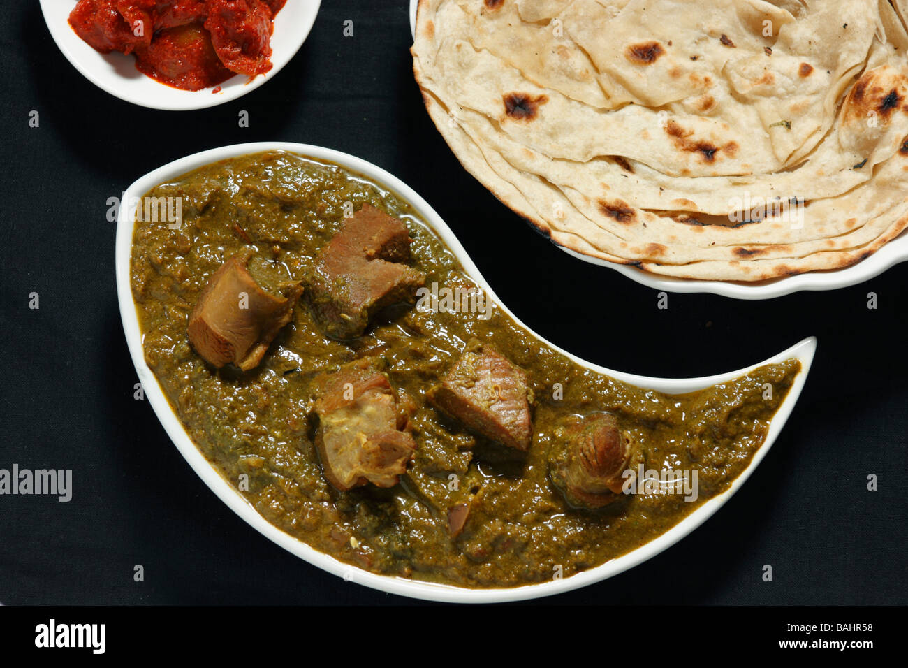 Saag montone viene preparato a partire da carni di montone cotte nel sugo Palak (spinaci) e spezie indiane e servita con roti & Pickle Foto Stock