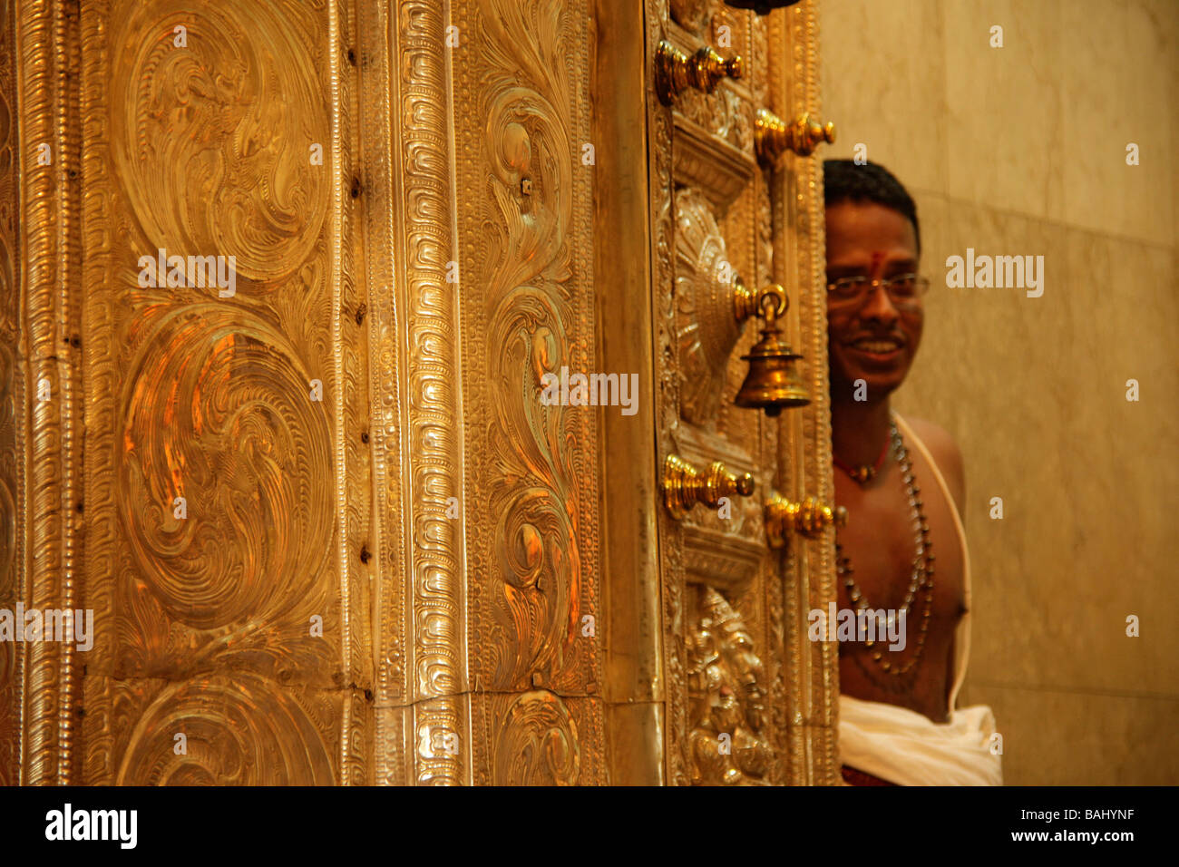 Sacerdote indù nascosto dietro una porta dorata in Sri Veeramakali Aman tempio in Singapore Asian Asiatisch Foto Stock