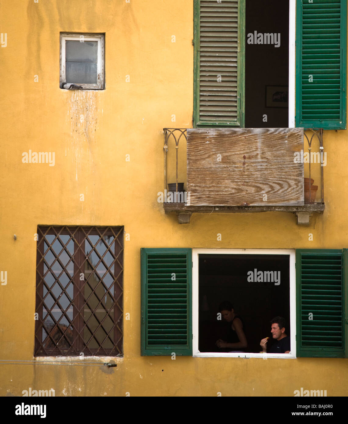 Un giovane seduto a pranzo in una finestra shutterd in Piazza Anfiteatro, Luca, Toscana, Italia Foto Stock