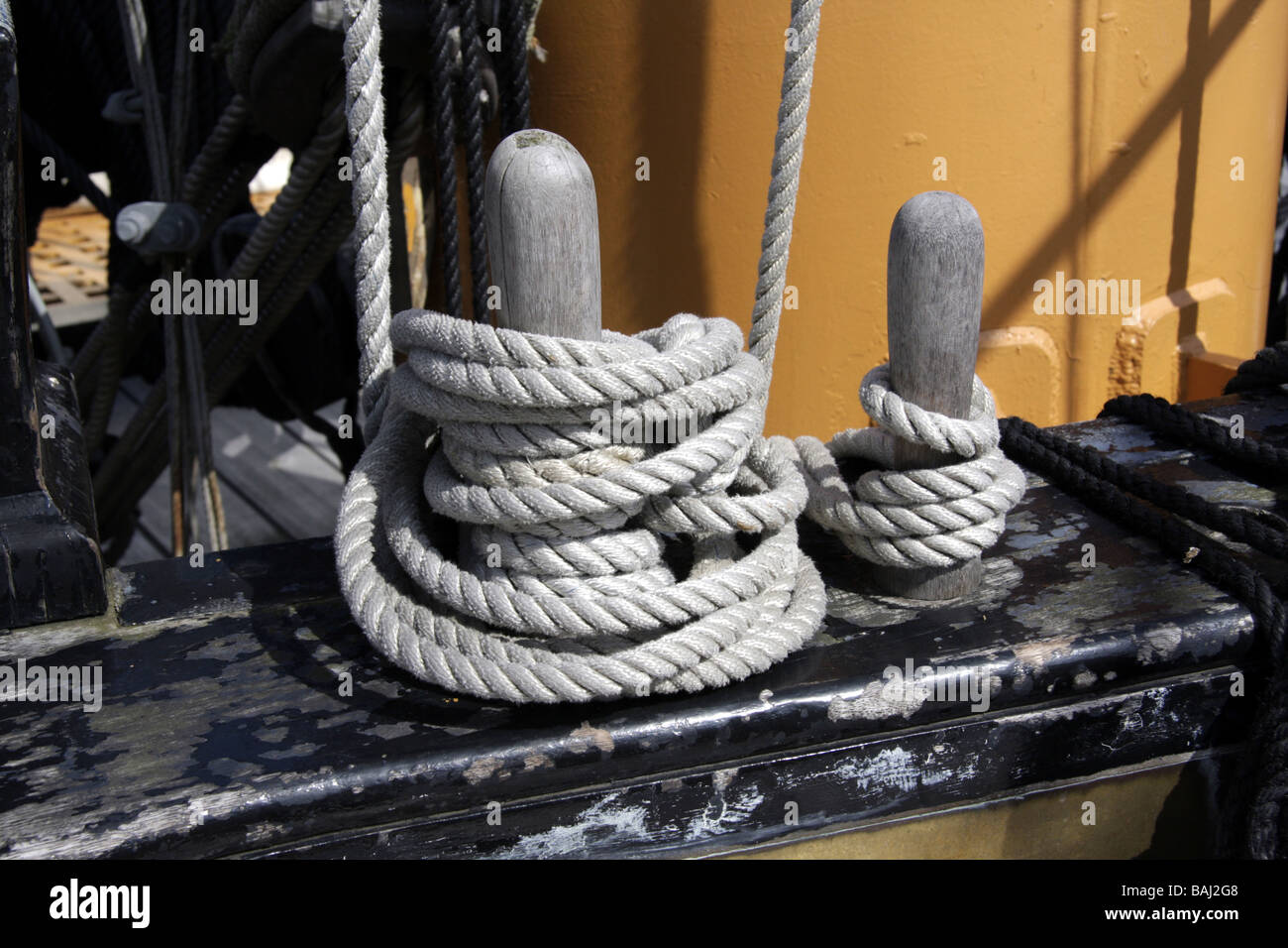 Funi avvolte attorno a perni belaying a bordo di una nave a vela Foto Stock