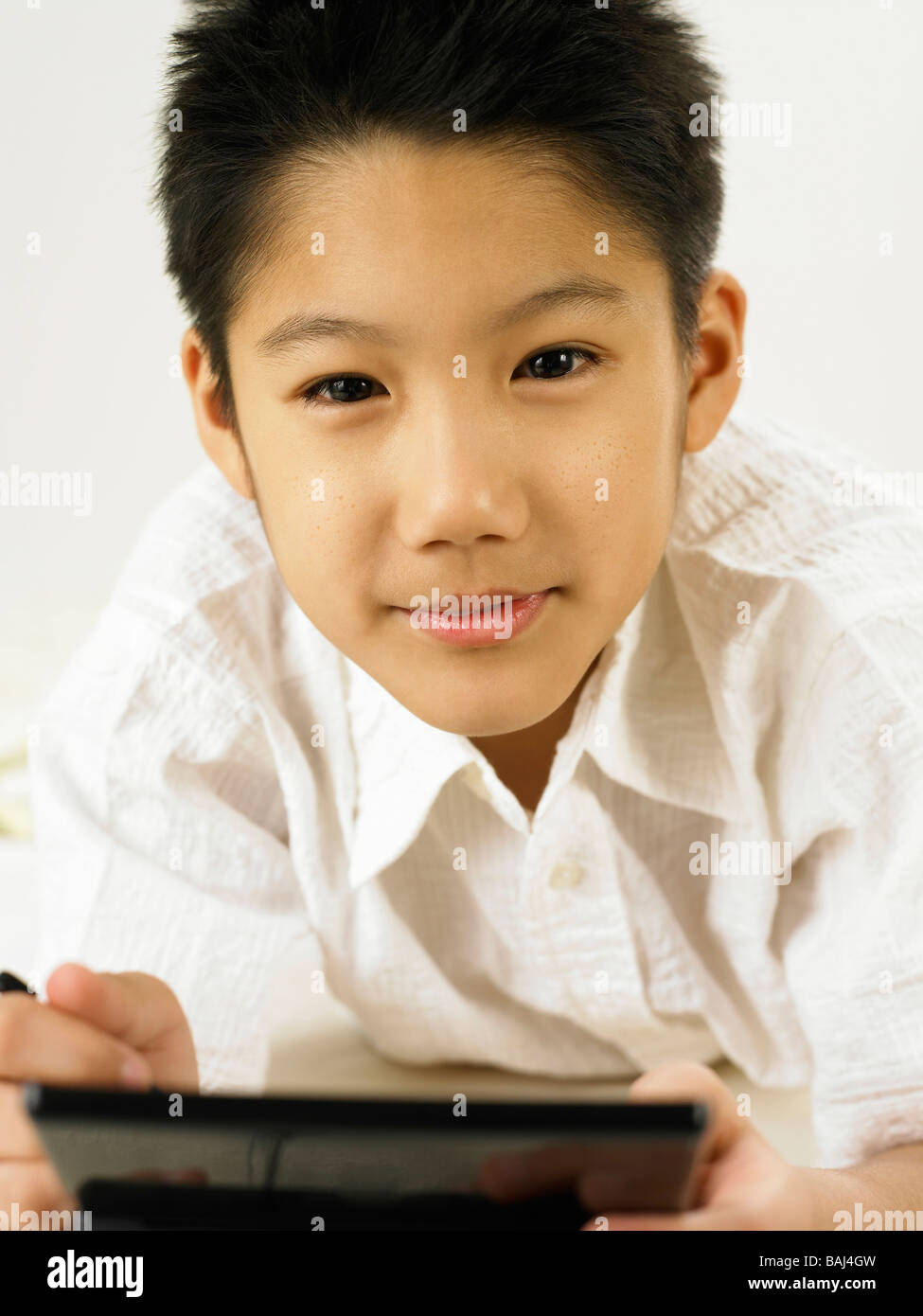 Ragazzo tenendo un portable video game e guardando la fotocamera Foto Stock