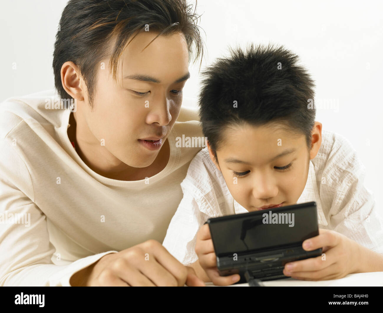 Padre e figlio la riproduzione video portatile di gioco presso la sala soggiorno Foto Stock