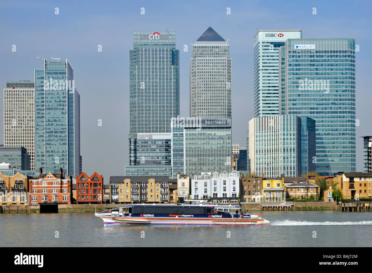 Loghi delle banche sugli uffici dei grattacieli e sugli appartamenti lungo il fiume presso l'area di sviluppo di Canary Wharf, London Docklands, River Tamigi, autobus clipper, Londra, Inghilterra, Regno Unito Foto Stock