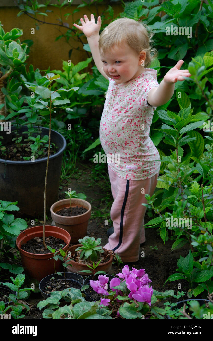 16 mese vecchio bambina imita un albero che cresce Foto Stock