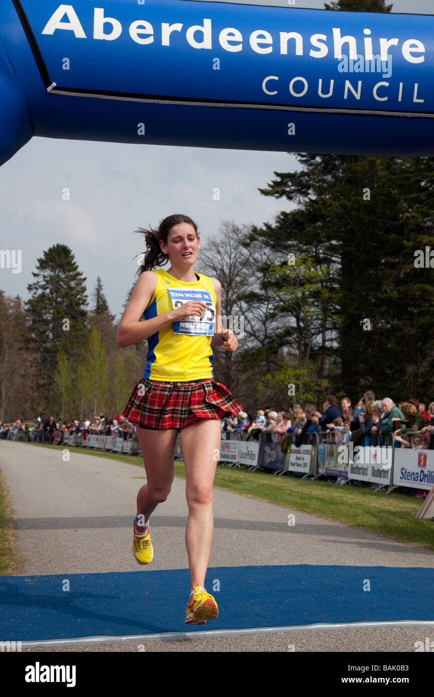 La donna in esecuzione in kilt in tartan. I concorrenti al traguardo al Aberdeenshire Consiglio eseguire 'Castello di Balmoral gare su strada" Sabato 25 Aprile 2009 Foto Stock