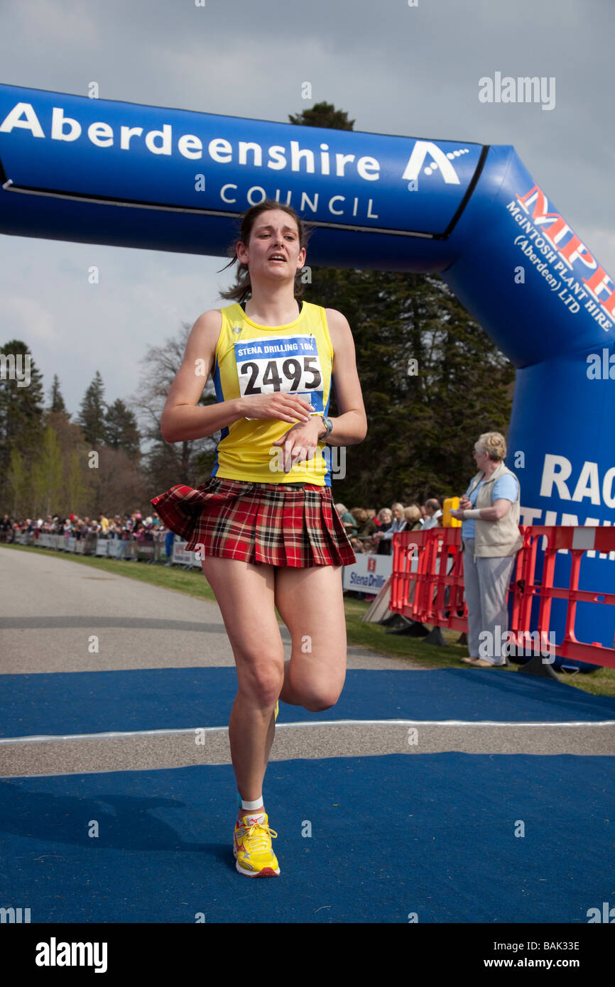 La donna in esecuzione in kilt in tartan. I concorrenti al traguardo al Aberdeenshire Consiglio eseguire 'Castello di Balmoral gare su strada" Sabato 25 Aprile 2009 Foto Stock