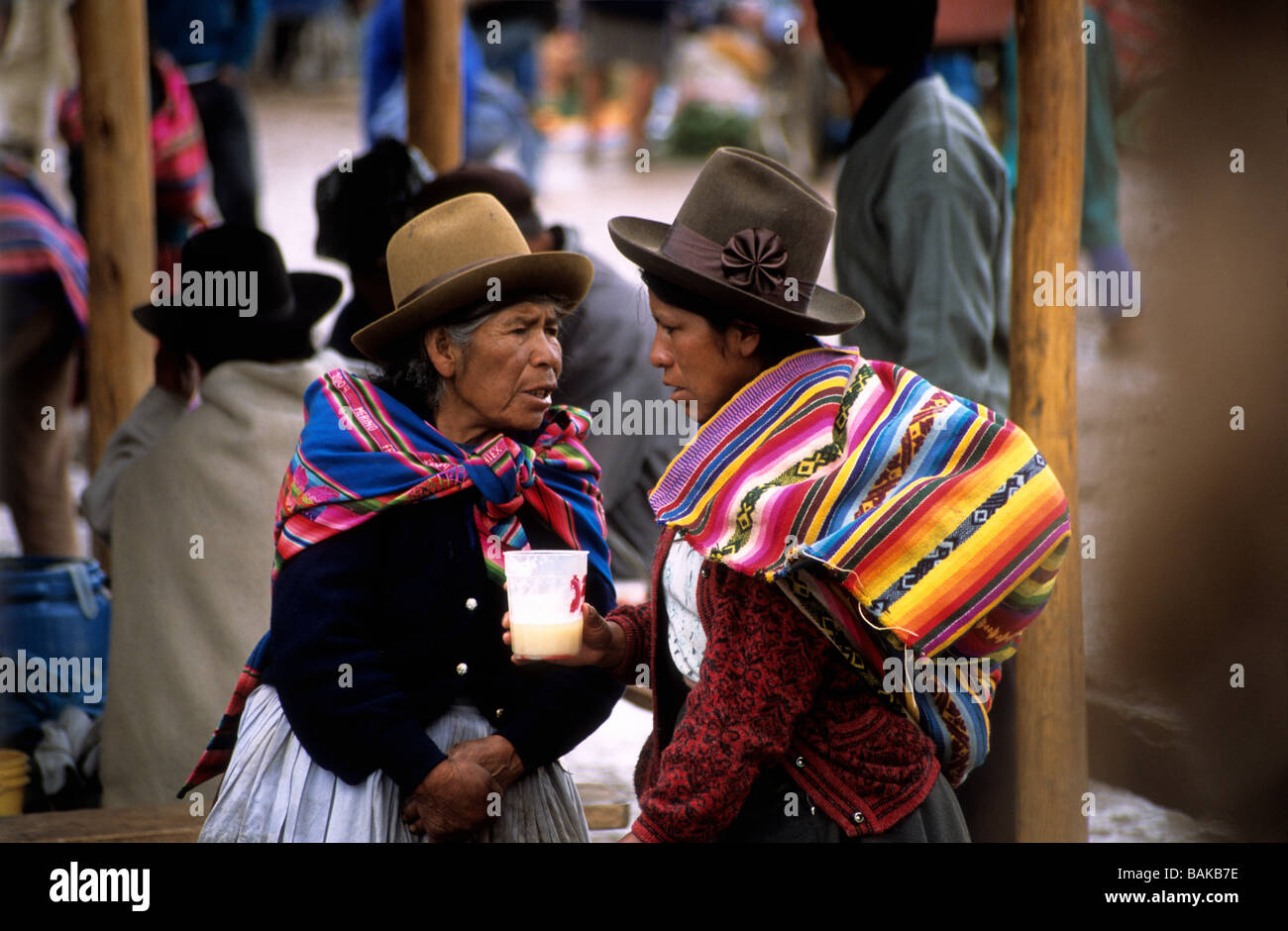 Il quechua ladies parlando e bevendo chicha (una tradizionale birra di mais ) , Chinchero mercato , Valle Sacra , Perù Foto Stock