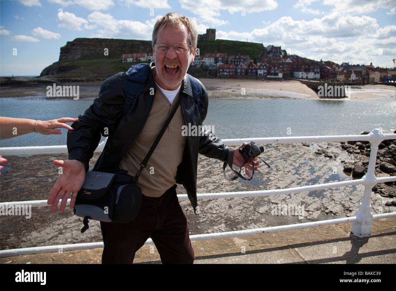 Uomo a Whitby guardando scioccato come egli constata che un gabbiano ha scompigliato in su la sua borsa, bird poo sorpresa Foto Stock