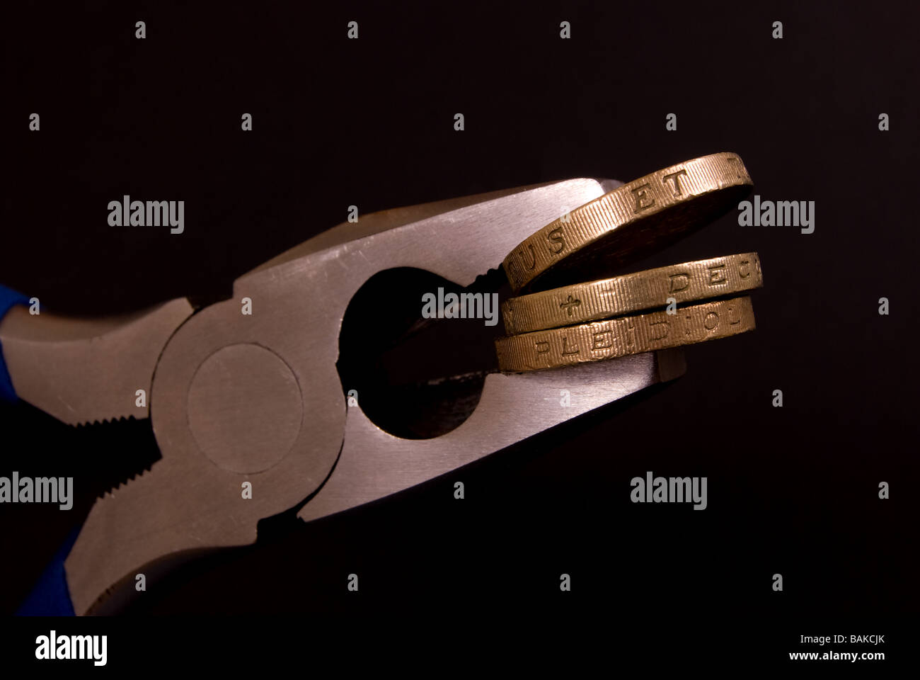 Una sterlina monete trattenute in pinze Foto Stock