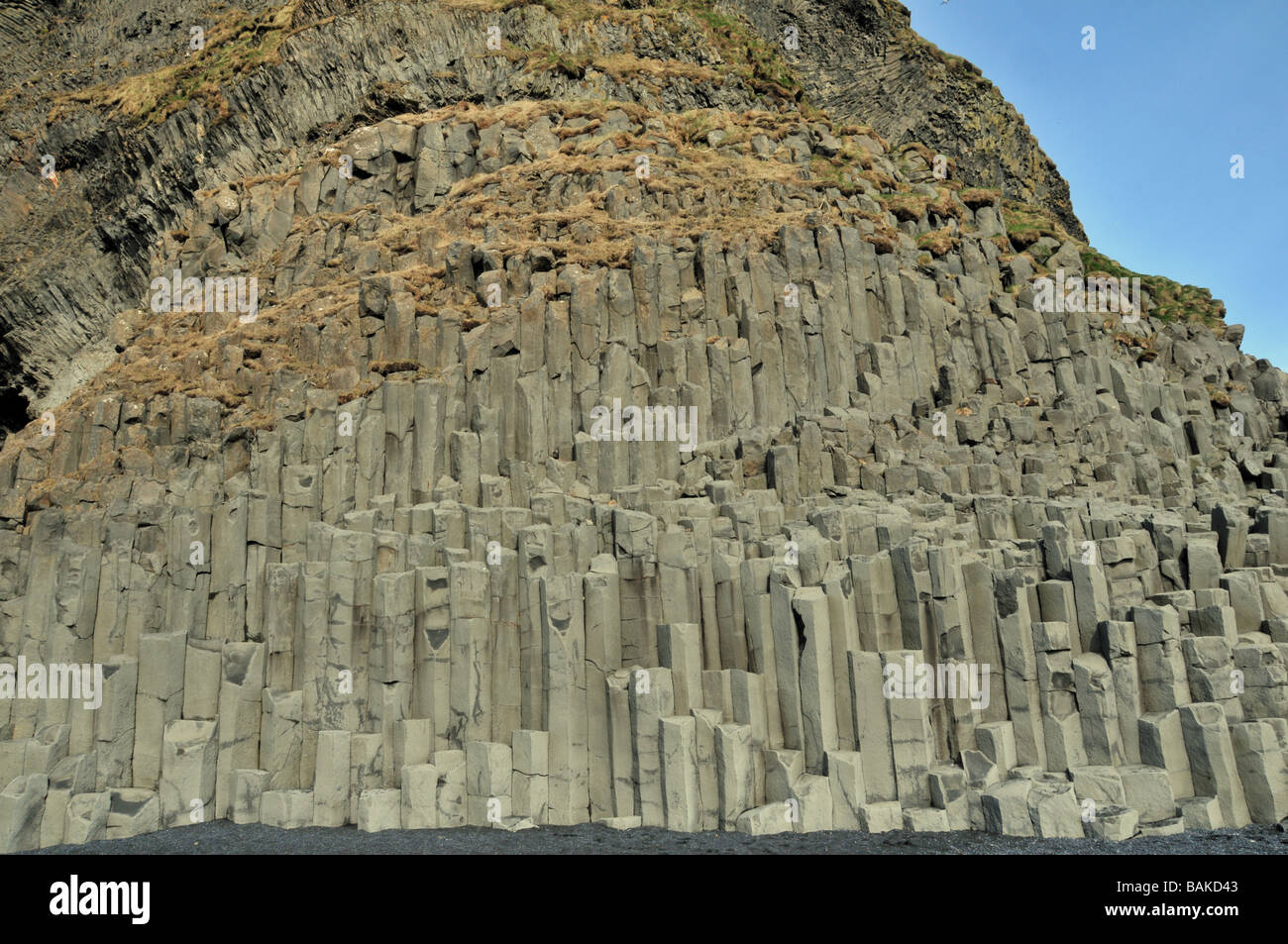 Imponenti colonne di basalto in scogliere al di sopra delle sabbie nere a Reynishverfi, Gardar, sulla punta meridionale di Islanda Foto Stock