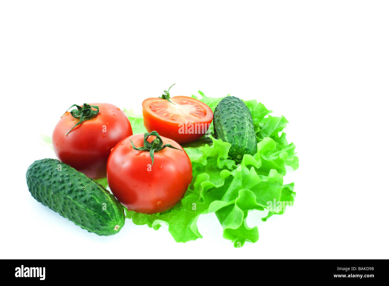 Due e mezzo rosso di pomodori e cetrioli di due su foglie di lattuga Foto Stock