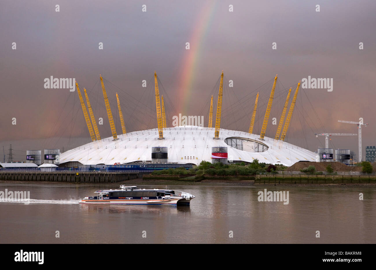 Vista dell'O2 Dome di arcobaleno sopra di esso e Thames Clipper commuter barca passando da Foto Stock