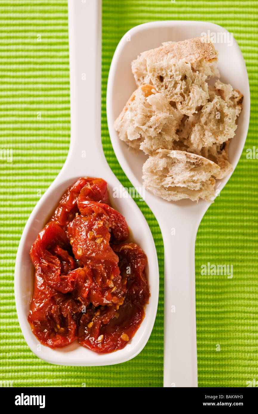 Bianco che serve cucchiai con olio di oliva di pezzi di pane e pomodori secchi Foto Stock