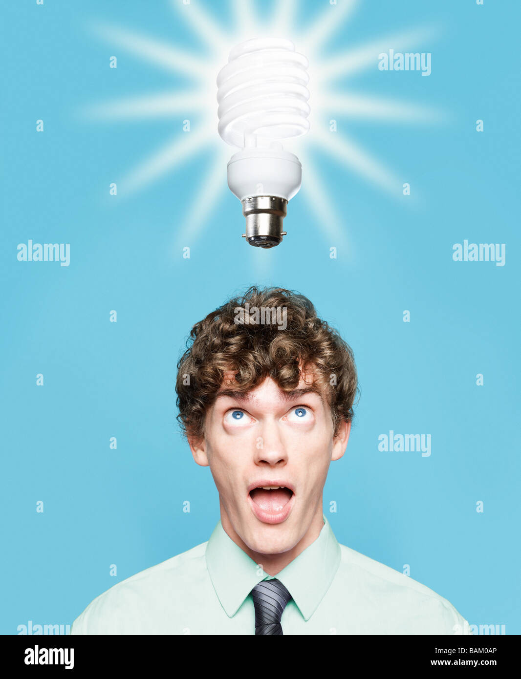 Un giovane uomo che guarda un risparmio energetico lampadina Foto Stock