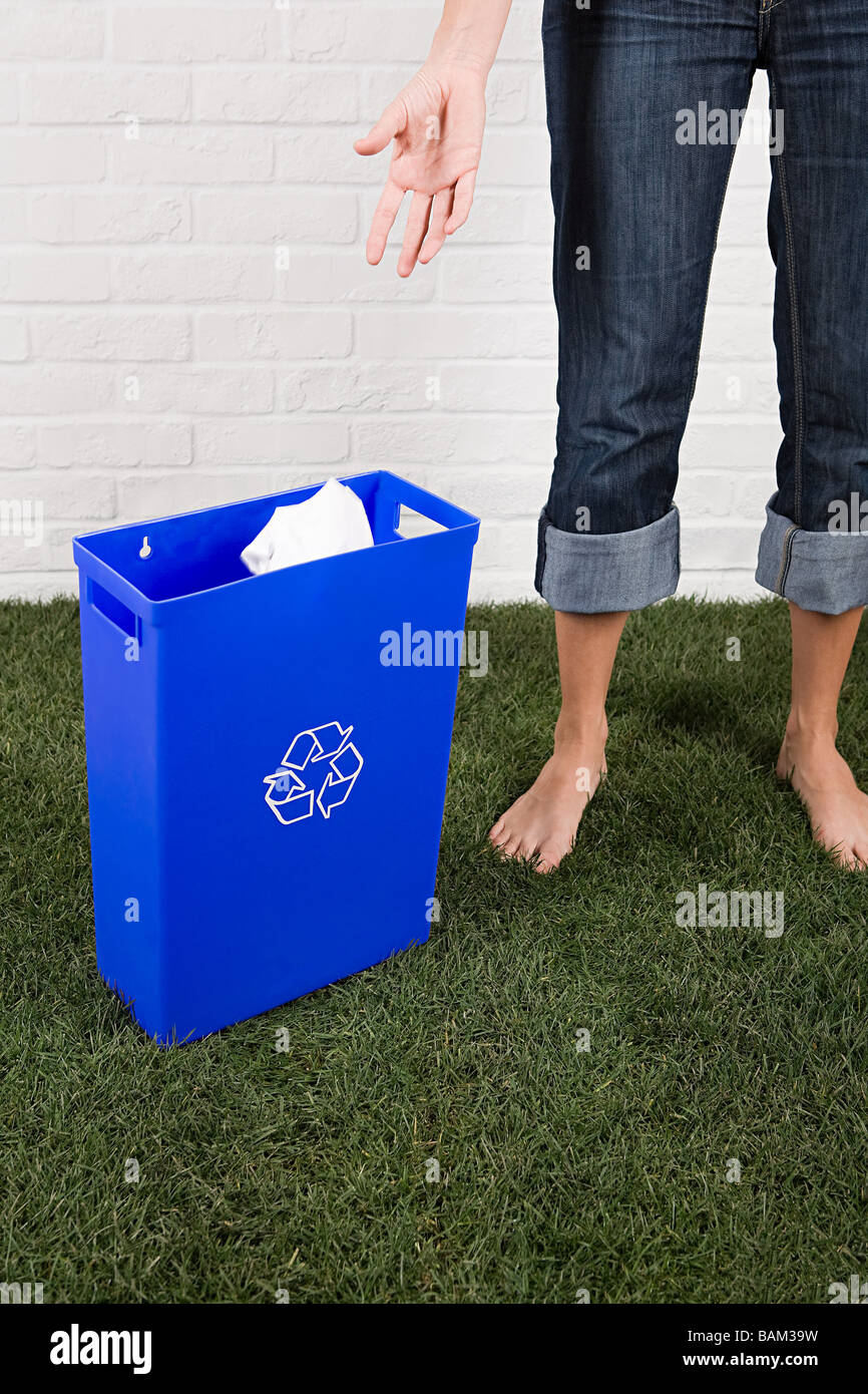 Una donna di gettare la carta in un contenitore di riciclaggio Foto Stock