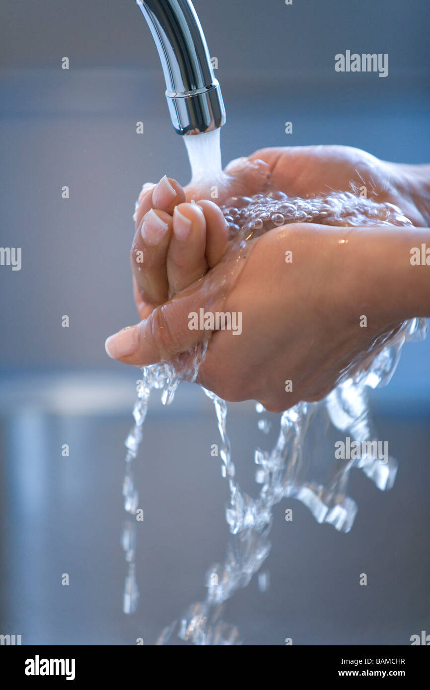 La donna sta lavando le mani sotto un rubinetto Foto Stock