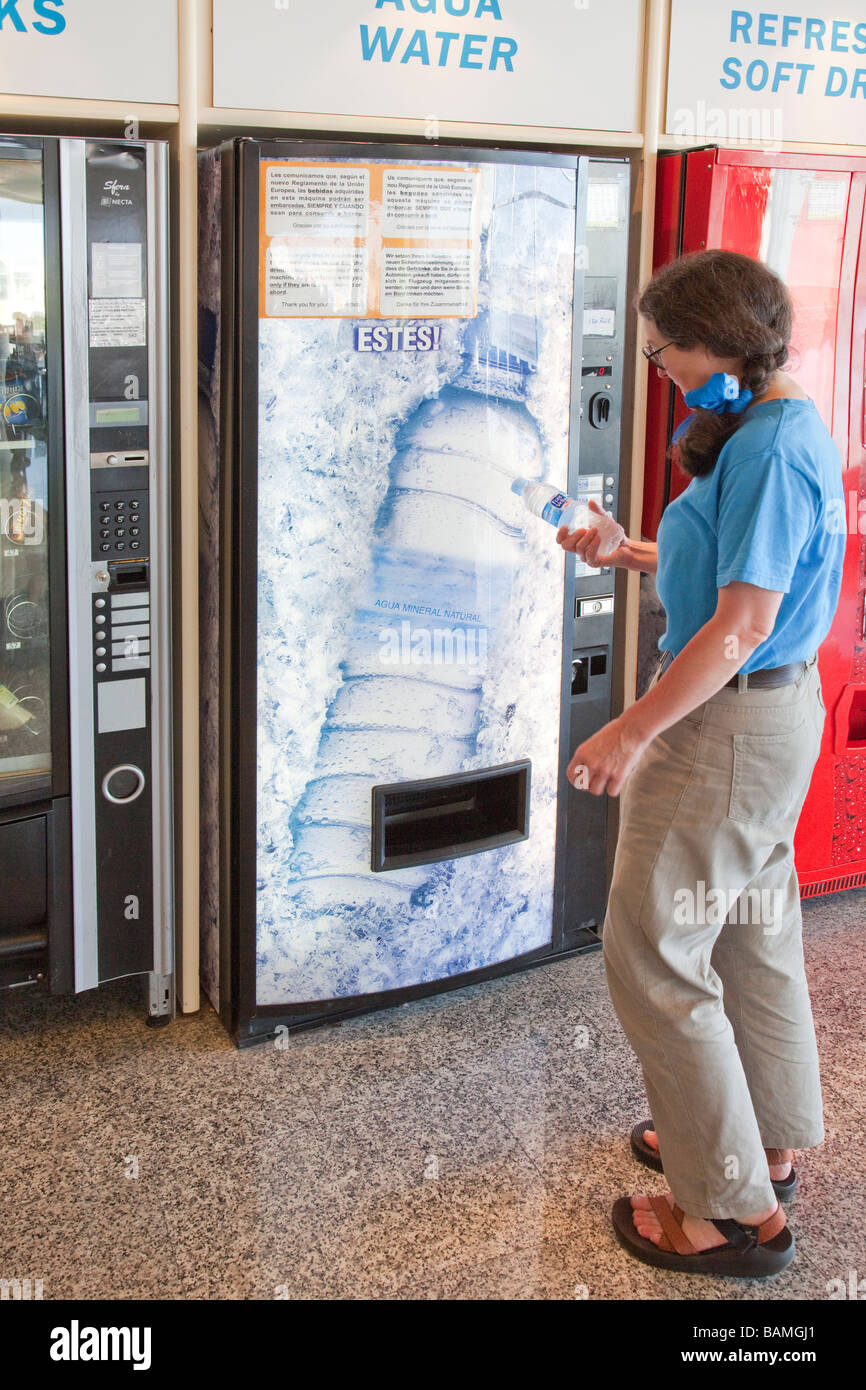 Donna viaggiatore di acquistare l'acqua dal distributore in airport lounge di partenza Palma Mallorca Spagna Spain Foto Stock