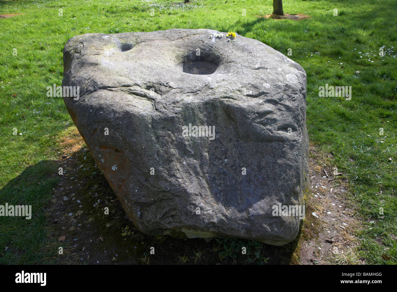 La grande pietra bullaun a antrim round tower conosciuto localmente come la pietra delle streghe come le impronte sono detti per essere fatte da una strega Foto Stock