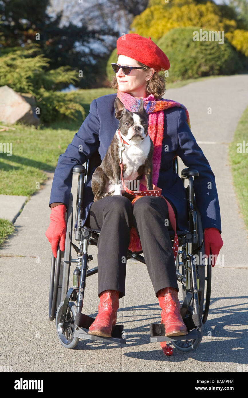 La donna in sedia a rotelle con il cane sul suo giro Foto Stock