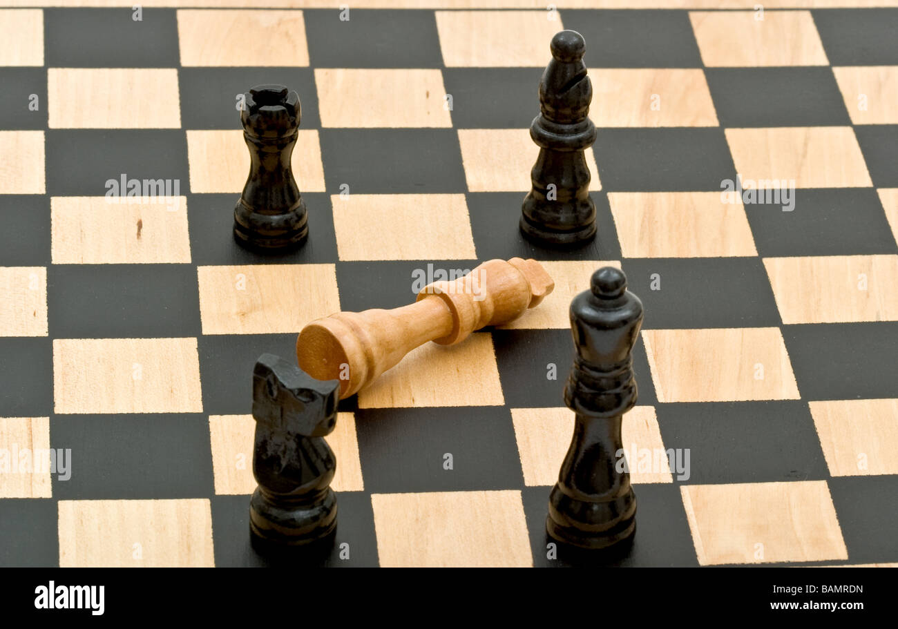 Pezzi di scacchi sulla scacchiera circostante il re con checkmated e giacente su un lato Foto Stock