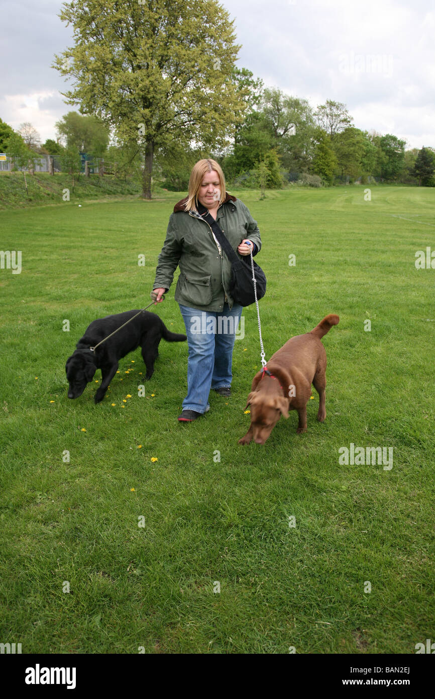 Donna anziana a piedi i suoi due gatti nel Parco Foto Stock