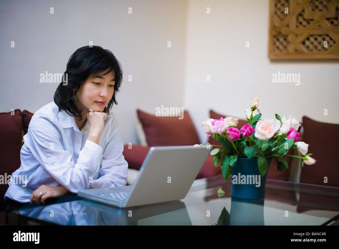 Donna asiatica utilizzando laptop in livingroom Foto Stock