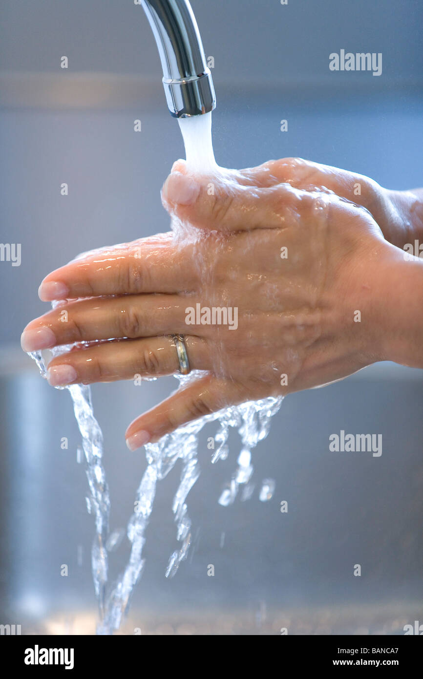 La donna sta lavando le mani sotto un rubinetto Foto Stock