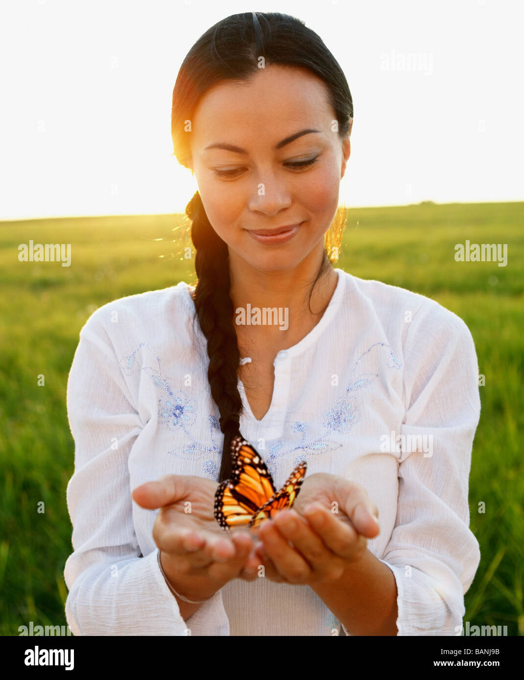 Donna asiatica holding farfalla in mani Foto Stock