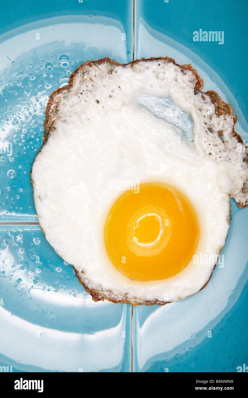 Uovo fritto su piastrelle blu Foto Stock
