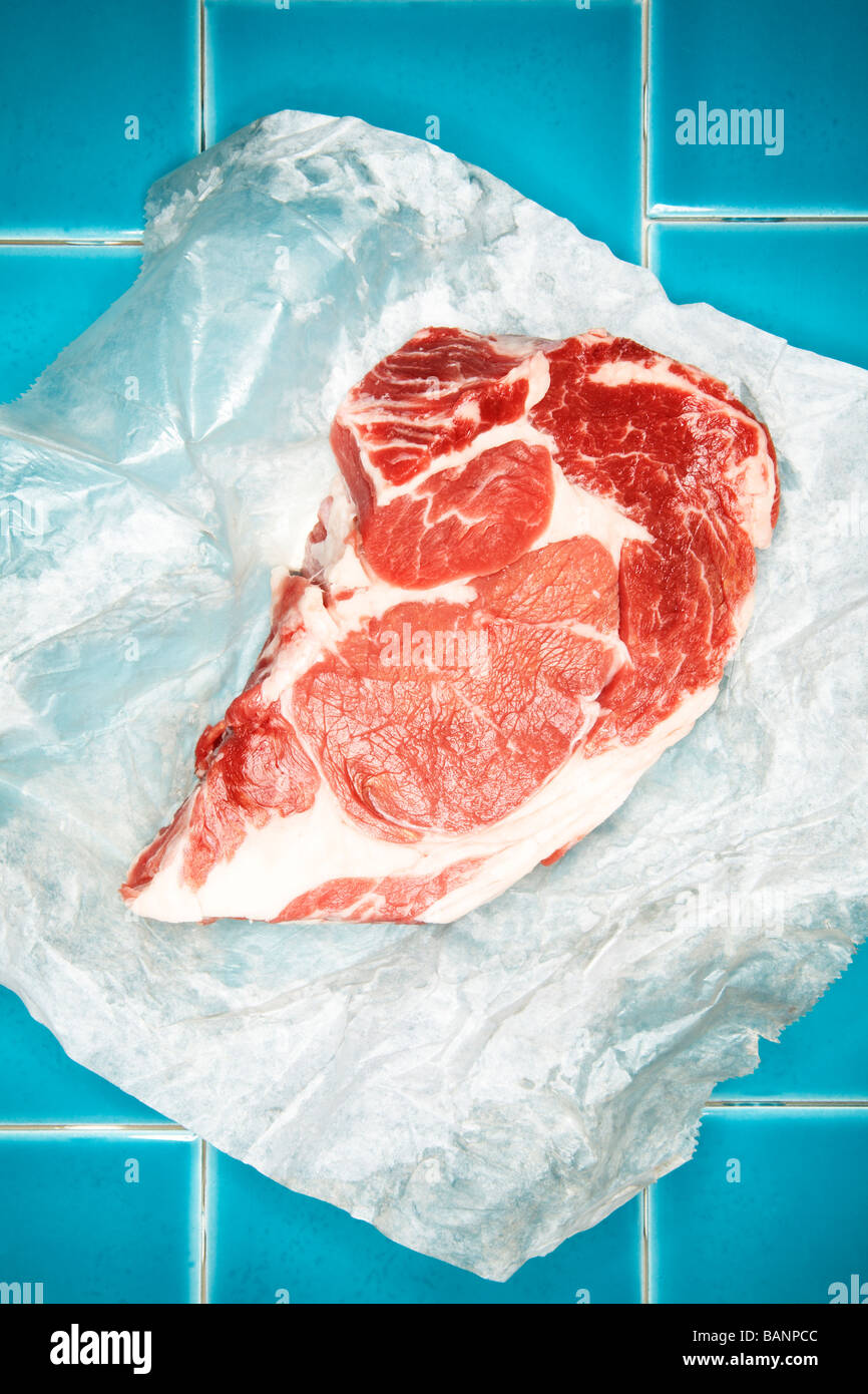 Materie bistecca su carta oleata su piastrelle blu Foto Stock
