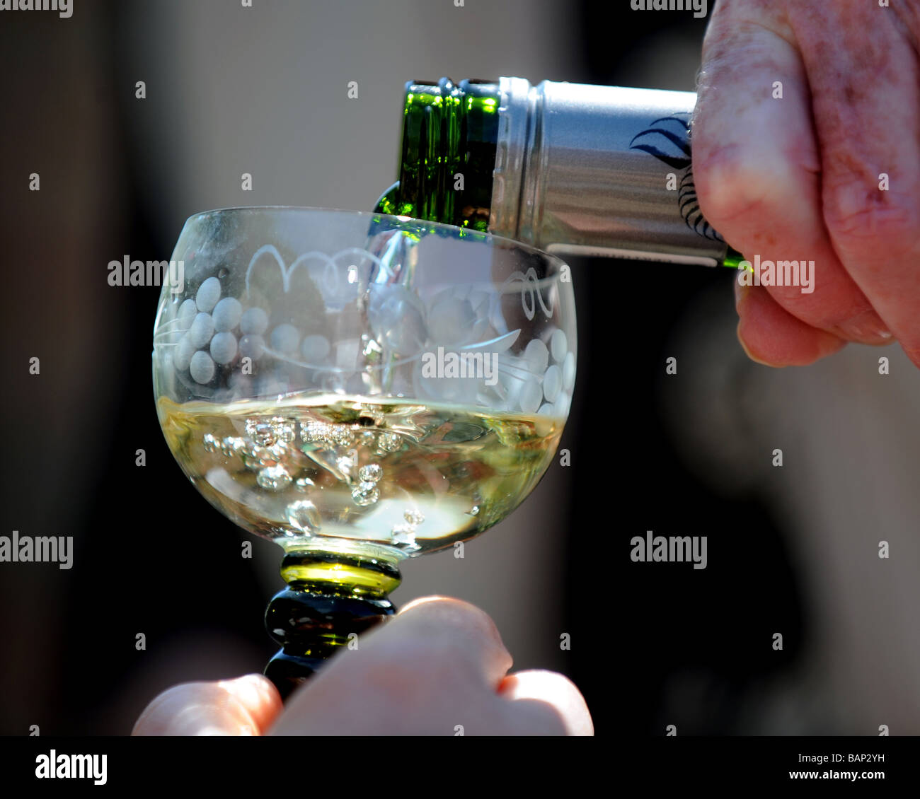 Un bicchiere di vino bianco che viene versato da un tappo a vite bottiglia Foto Stock