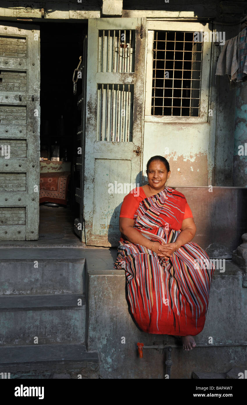 Una donna in un sari rosso rilassante in un Ahmedabad Street Foto Stock