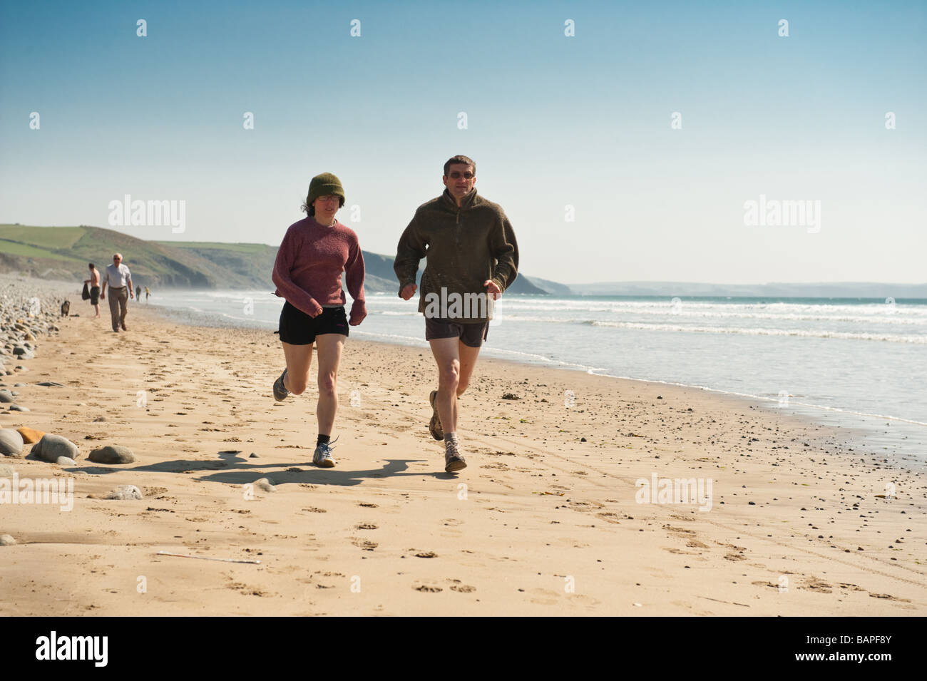 Un paio di percorso jogging sulla spiaggia Newgale Pembrokeshire Coast National Park calda primavera pomeriggio Wales UK Foto Stock