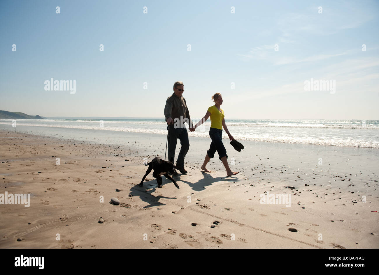 Una giovane coppia camminando mano nella mano con il loro cane sulla spiaggia Newgale Pembrokeshire Coast National Park Galles pomeriggio estivo Foto Stock