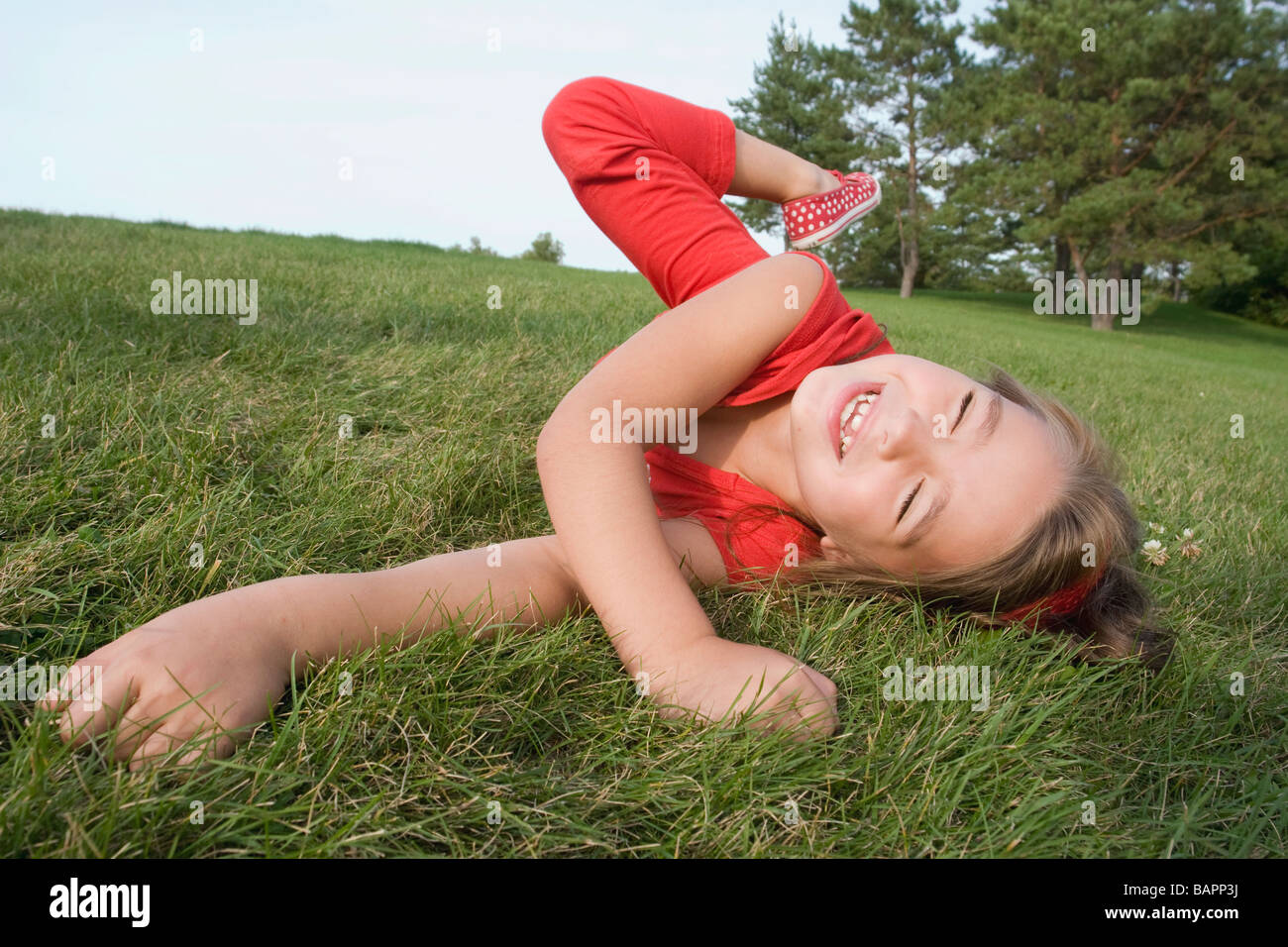 6 anno vecchia ragazza rotolamento su erba, Winnipeg, Manitoba, Canada Foto Stock