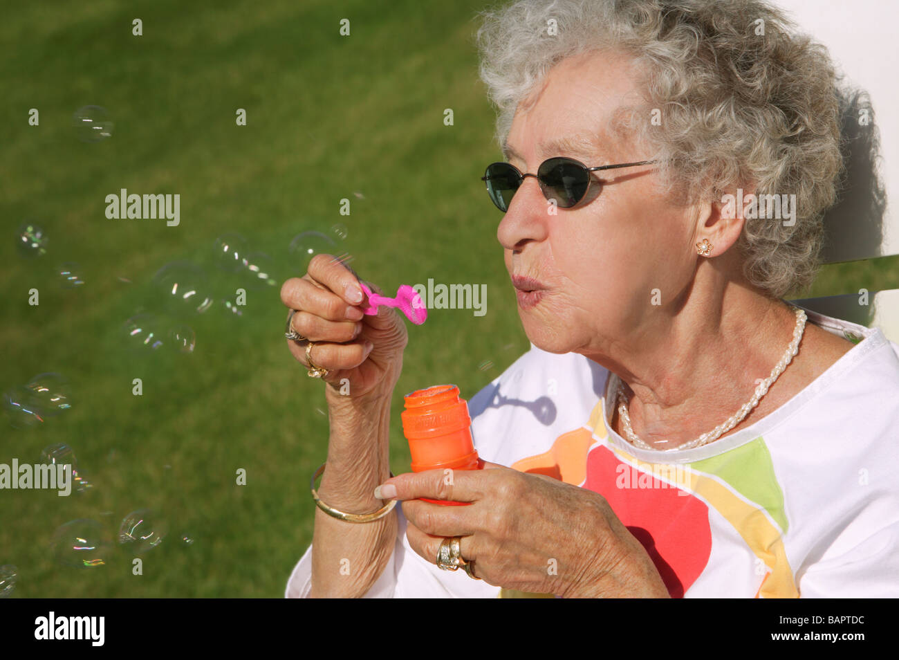Giocoso senior; Senior donna soffiare bolle Foto Stock